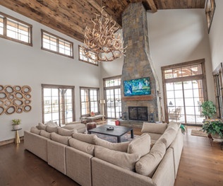 Main salon with two-story stone fireplace and antler chandelier